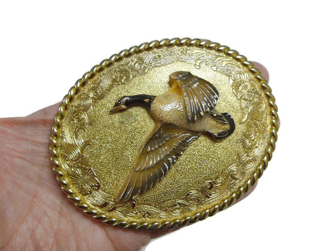 http://shopthrilling.com/cdn/shop/products/1978-raintree-_E2_84_A2-flying-duck-belt-buckle-by-1978-raintree-_E2_84_A2-product-image__67ehvnnxw.jpg?v=1612590842